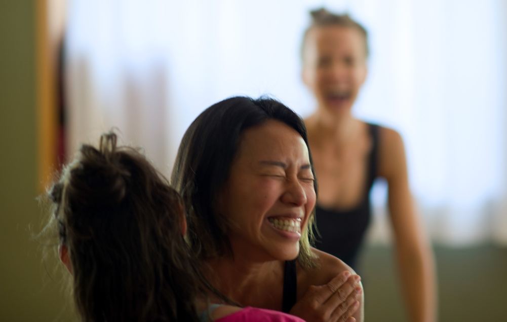 Zwei Teilnehmerinnen lachen und umarmen sich nach der Yogastunde
